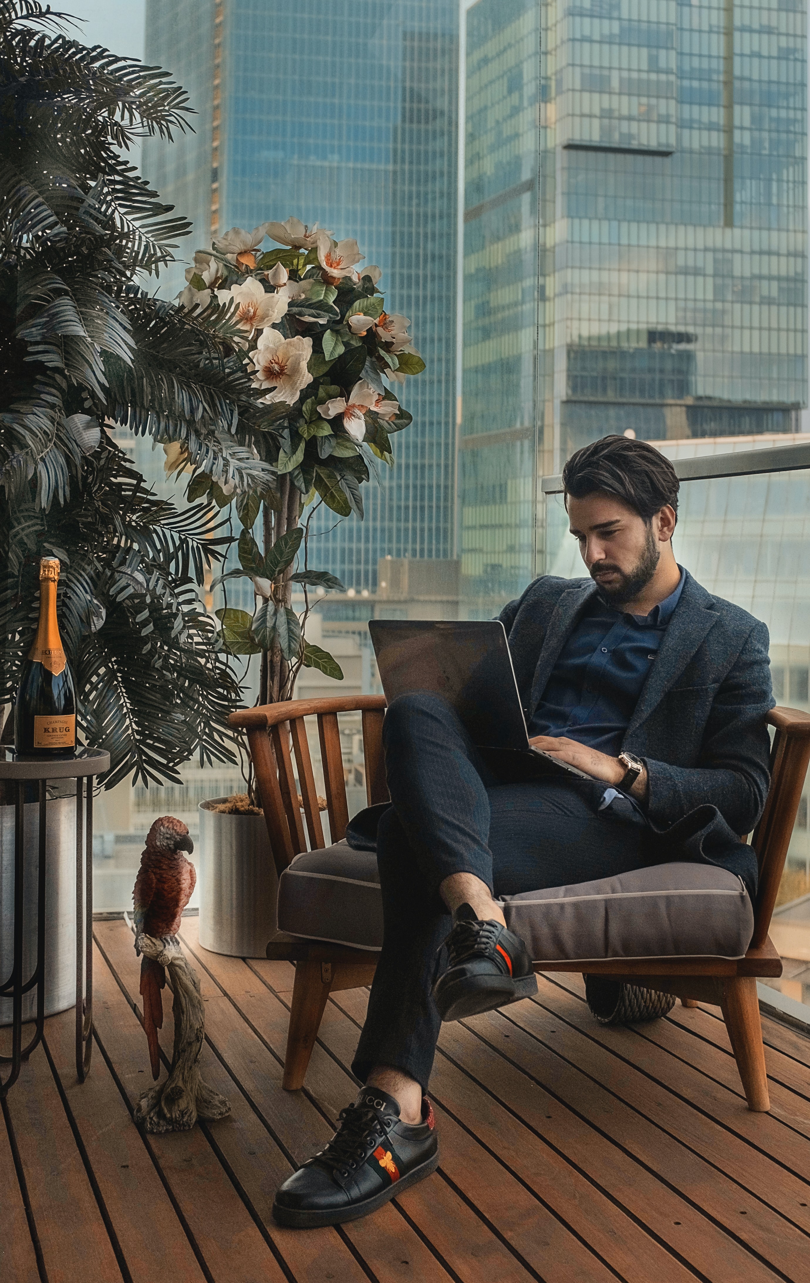 Rich guy on laptop in a penthouse with parrot and Krug champagne