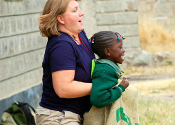 A motivated volunteer helps a girl in a sack race