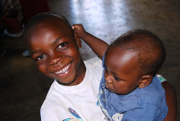 A pair of smiling brothers receive a rice donation from Child of Destiny